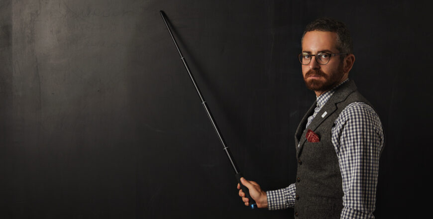 serious-bearded-professor-plaid-shirt-tweed-vest-wearing-glasses-looking-condemn-shows-something-school-black-board-with-his-pointer.jpg